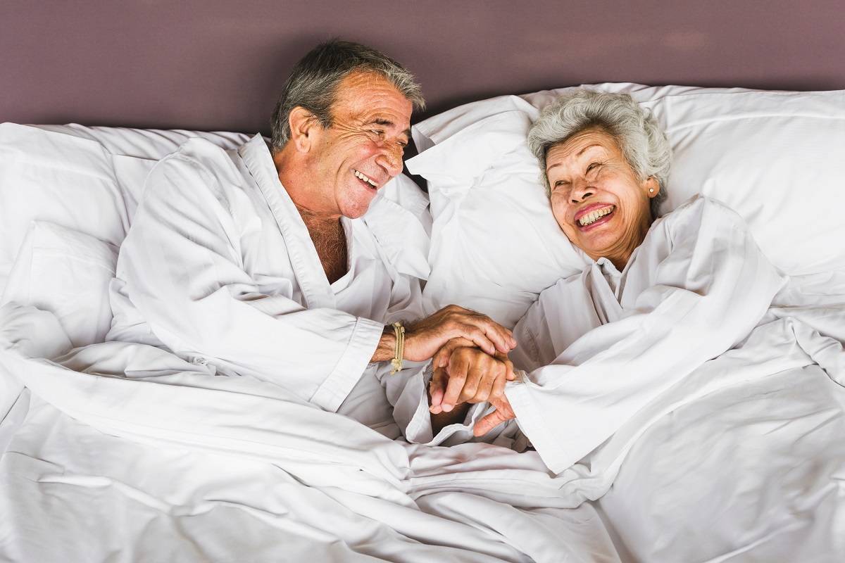 senior couple lying in hotel bed on marriott, senior discount hotels for senior